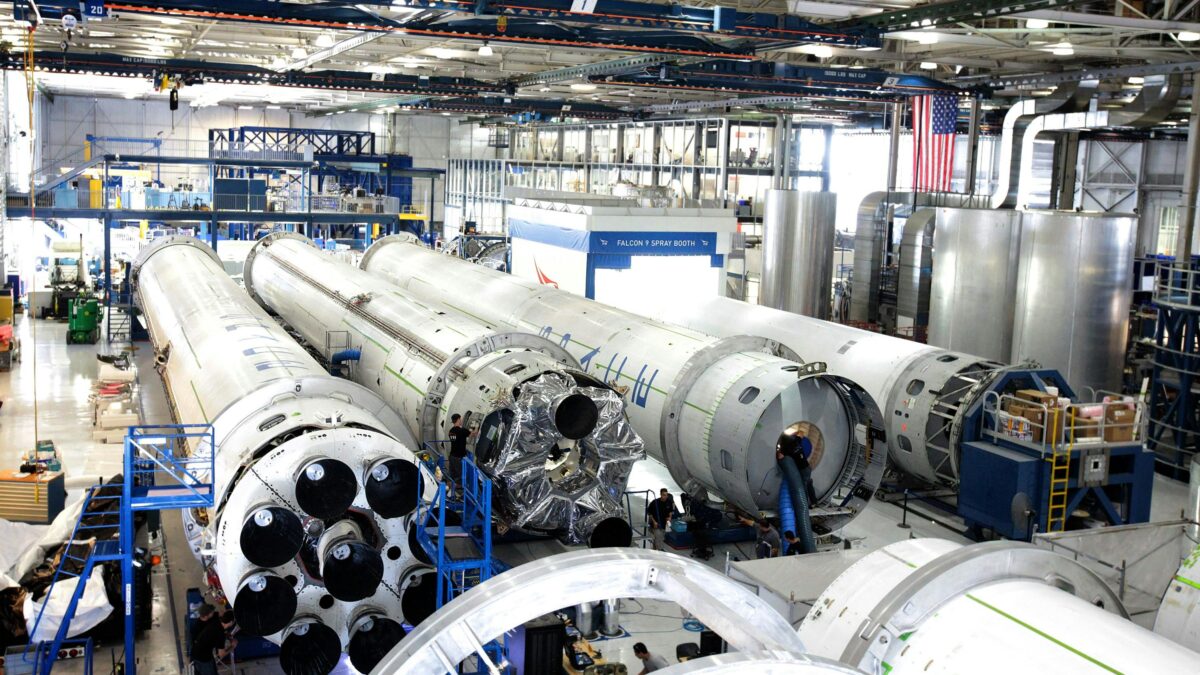 View of a spacecraft assembly line with rockets in a spacious hangar.